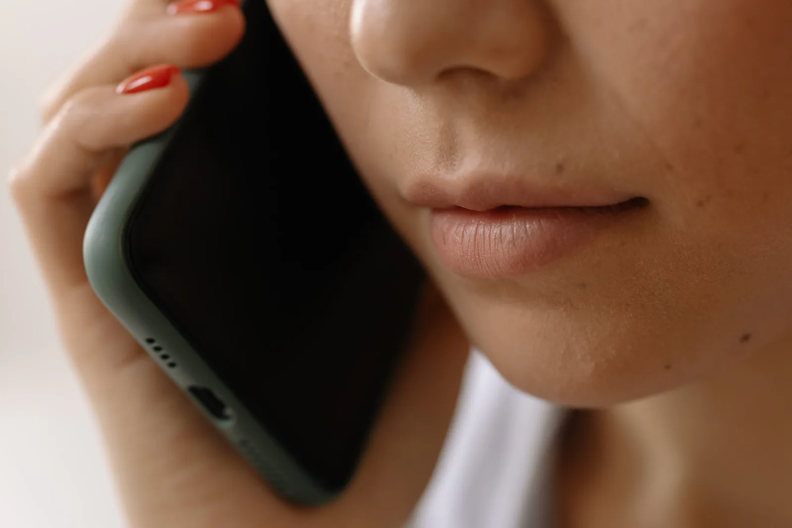 A close-up image of a woman holding a smartphone to her ear, emphasizing communication.