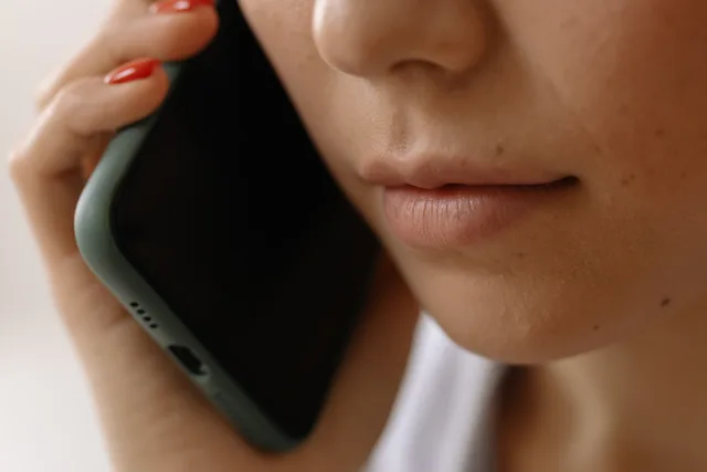 A close-up image of a woman holding a smartphone to her ear, emphasizing communication. Capturing permission before passing contact details